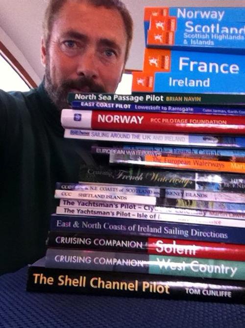 Paul Shard with stack of cruising guides for recent cruise around the UK and Brittany Coast of France © Sheryl Shard